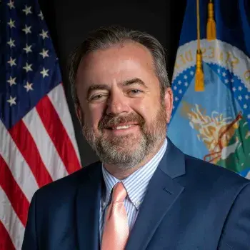 John Berge headshot with flags in the background